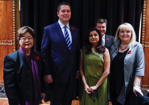 Gruppe von Menschen vor schwarzem Vorhang mit Holzwand im Hintergrund, die scheinbar Mitglieder der Freien Demokraten bei einer Versammlung sind.