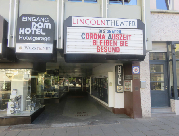 Das Lincoln Theater in Berlin, ein gläsernes Gebäude mit einer Texttafel, sieht von innen belebt aus und zeigt verschiedene Gegenstände.