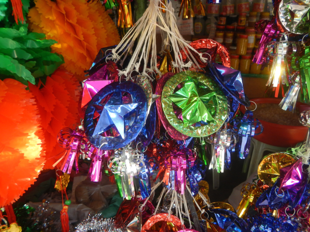 Eine festliche Decke mit bunten Papierlaternen, Bändern und Dekorationen, die über Regalen mit Flaschen im Hintergrund hängen.