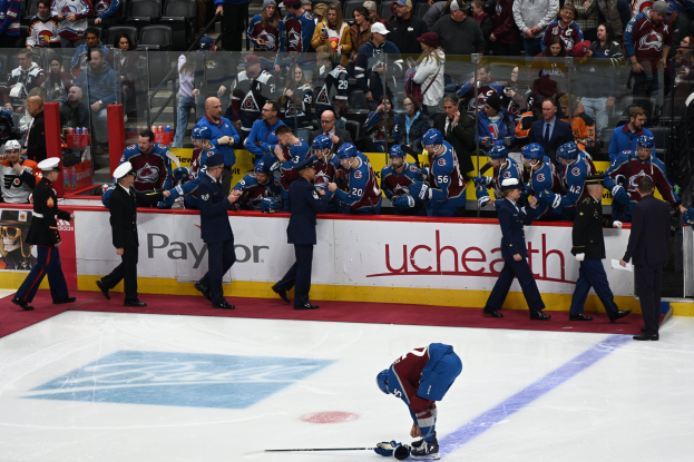 Hockeyspieler auf dem Eis umgeben von Zuschauern und Teammitgliedern während eines Spiels zwischen Colorado Avalanche und San Jose Sharks am 24. März 2015.