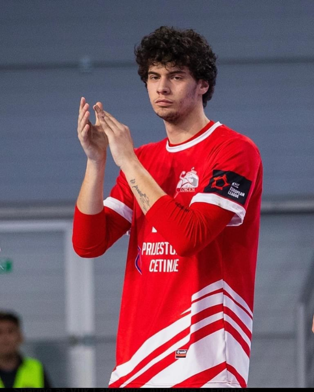 Ein Mann in rot-weißem Shirt klatscht in der Vordergrund mit einer anderen Person und einer Wand im Hintergrund, mit Text 'Copenhagen Futsal Club - Foto 1' unten.