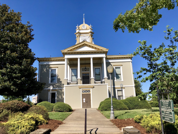 Großes Backsteingebäude mit einem Glockenturm, umgeben von Fenstern, Türen, Säulen und einem Dach, als das wiedereröffnete alte Rathaus bezeichnet.