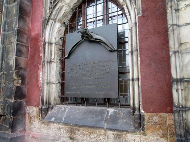 Steingebäude mit einem Fenster und einer Holocaust-Gedenktafel mit Inschrift.