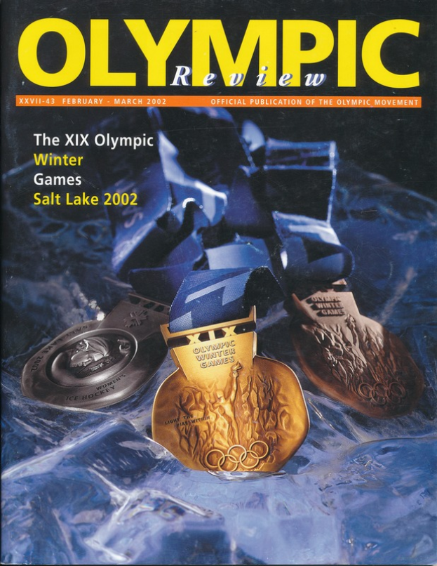 Ein Buch mit dem Titel "Olympic Review Magazine" mit mehreren Medaillen in verschiedenen Größen und Farben und fetter Schrift auf dem Cover.