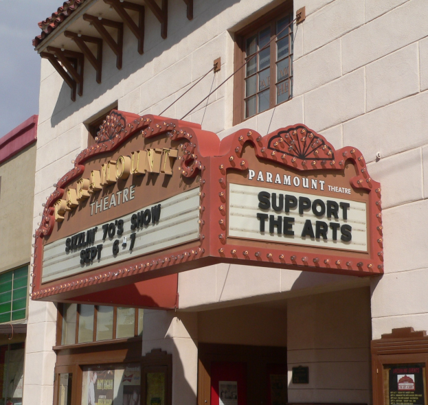 Außenansicht des Paramount Theatre in Sacramento, Kalifornien, mit Glasfenstern und -türen, einem "Support the Arts"-Schild und einem sichtbaren Himmel im Hintergrund.