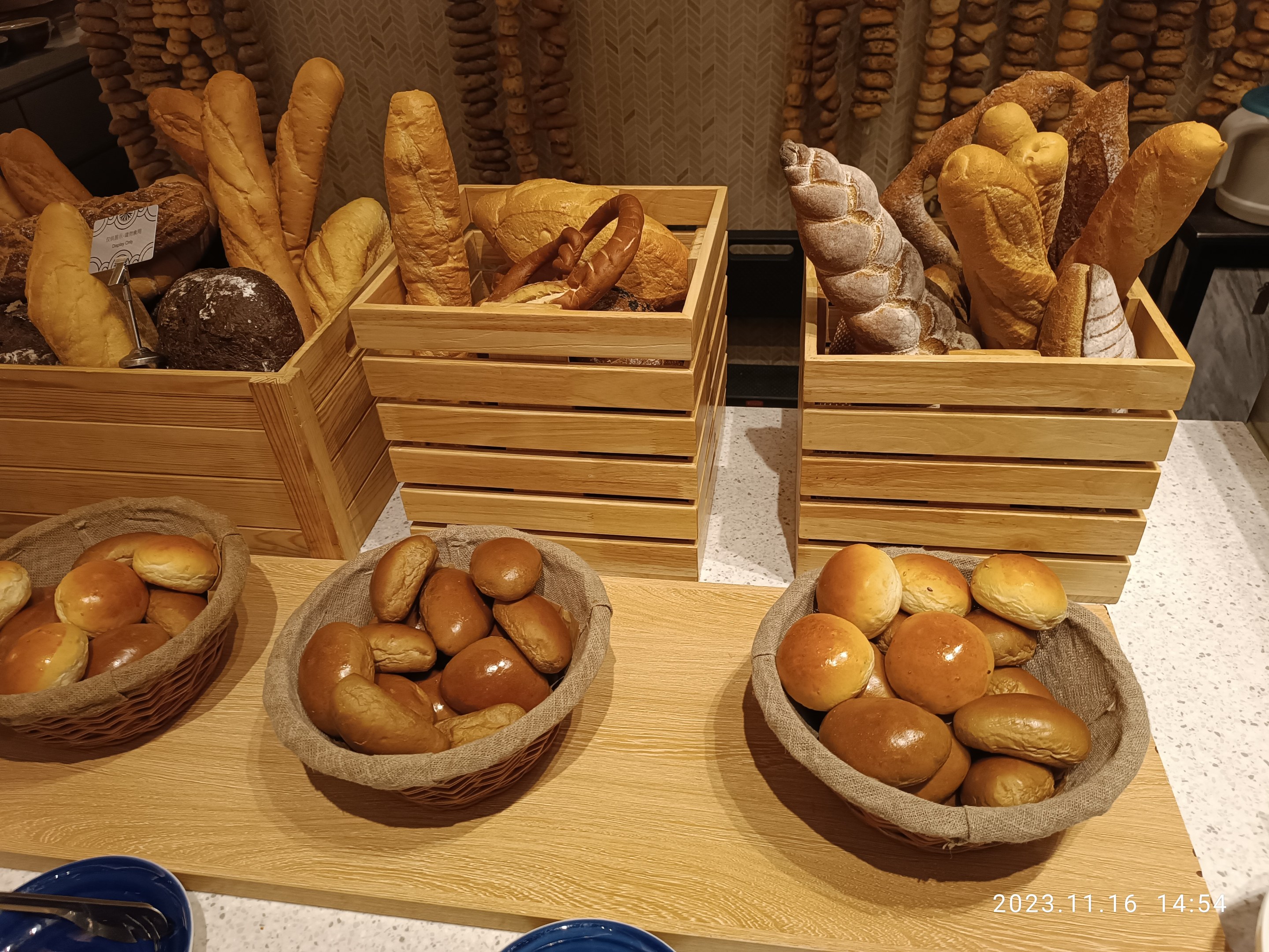 Holztisch mit Körben voller Brot, Tellern und Löffeln in einer Pariser Bäckerei.