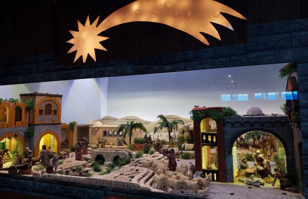 Eine Krippe-Ausstellung im Museum mit Menschen, Tieren, Häusern, Bäumen und anderen Gegenständen und einer Lichtquelle von oben.