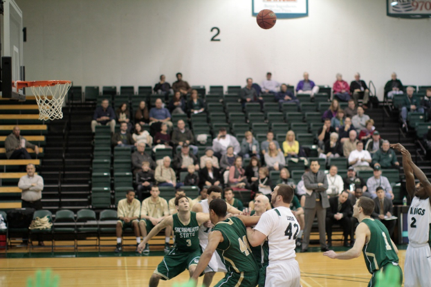 Ein Basketballfeld mit spielenden Spielern und Zuschauern auf den Tribünen.