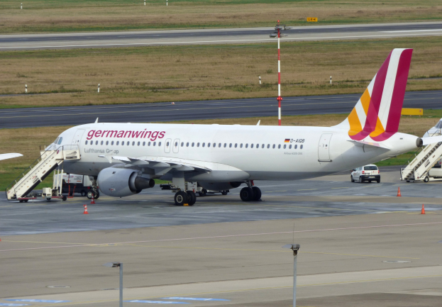 Germanwings Airbus A320-200 am Frankfurter Flughafen geparkt mit Bodenfahrzeugen, Verkehrskegeln, Versorgungsmasten und Grasfläche im Hintergrund.