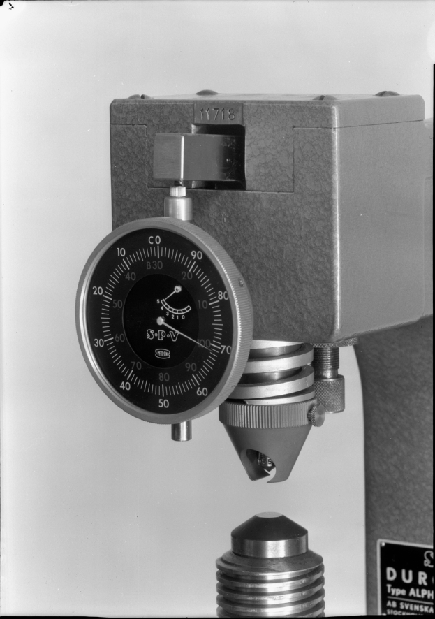 Ein Schwarz-Weiß-Foto eines Messgeräts, eine Maschine zur Messung der Dicke eines Metallstücks.