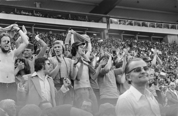 Schwarzes und weißes Foto einer vollen Tribüne mit einigen Zuschauern, die Brillen tragen.