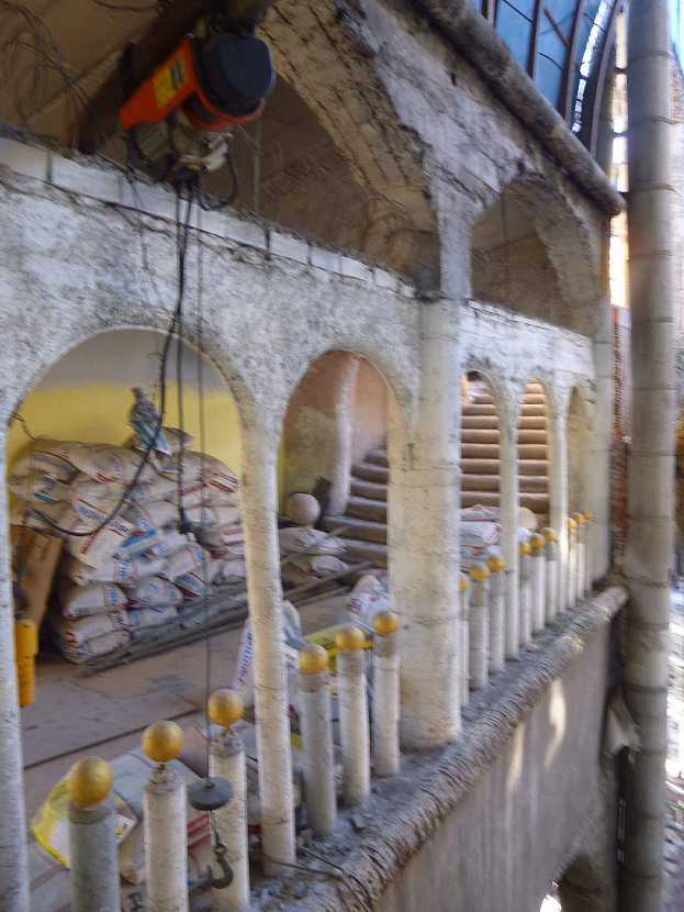 Altes Gebäude mit Bogengang, Säulen und Treppen undergoes Renovierung, featuring scattered Tools, Materials, and scattered objects including bags.