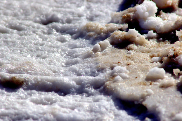 Nahaufnahme von weißem, flauschigem Schnee, der den Boden mit einer dicken Salzschicht in der Mitte bedeckt.