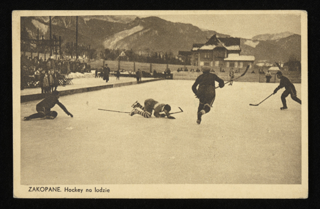 Ein altes Schwarz-Weiß-Foto von Menschen, die Hockey auf einem Eisstadion spielen, mit Gebäuden, Bäumen, Pfählen und Bergen im Hintergrund und Text unten.