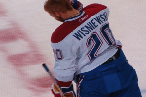 Ein Hockey-Spieler in einem "Wisniewski"-Trikot steht auf dem Eis und hält einen Hockey-Schläger in der Hand.