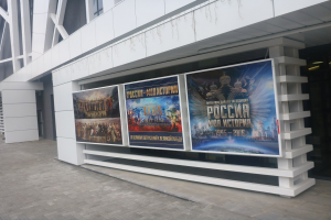 Ein Gebäude mit einem großen Plakat, das die Eröffnungszeremonie der Olympischen Spiele in Moskau ankündigt und von rechts beleuchtet wird.