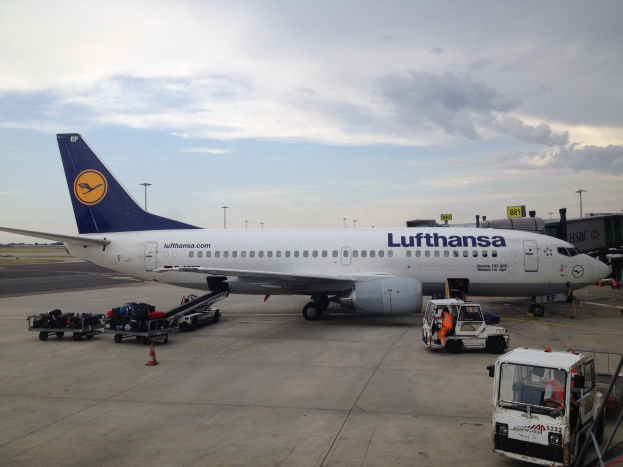 Lufthansa Airbus A320-200 am Frankfurter Flughafen mit Bodenfahrzeugen, Wagen, Verkehrskegeln, Beschilderung und einer bewölkten Himmel.