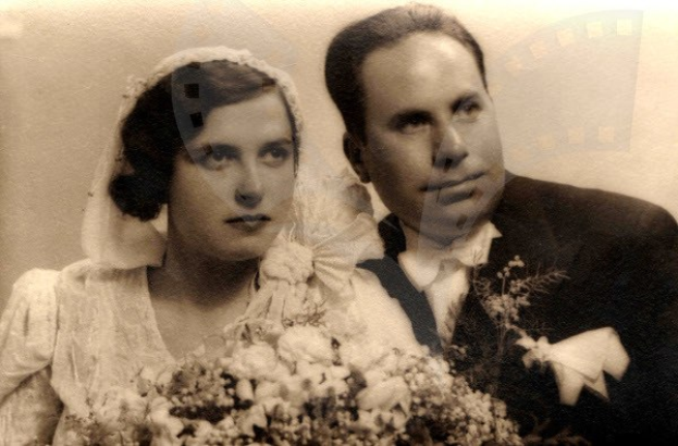 Schwarz-weißes Foto eines Mannes und einer Frau an ihrem Hochzeitstag, die Frau in einem weißen Kleid mit einem Strauß Blumen, beide strahlend glücklich.