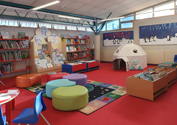 Eine Kinderbibliothek voller Bücher, Möbel, Bildungsausstellungen und natürlichem Licht von großen Fenstern.