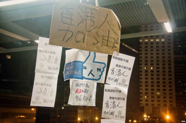 Menschen vor einem nächtlich beleuchteten Gebäude mit Schildern von der Decke protestierend gegen ein Social-Media-Verbot