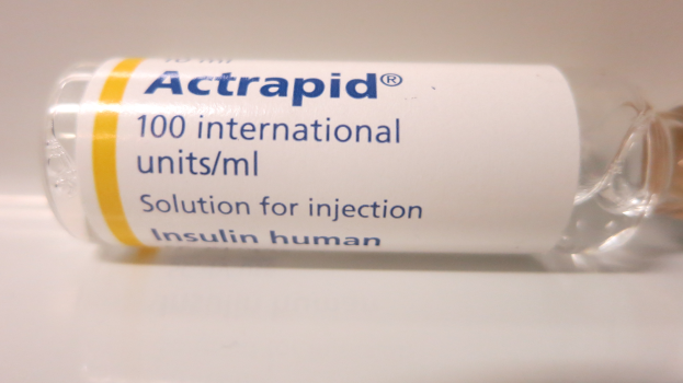 Ein Fläschchen Actrapid 100 internationale Einheiten/ml Lösung zur Injektion Insulin human auf einer weißen Oberfläche, beschriftet mit "Actrapid" in fetter schwarzer Schrift.