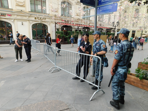 Polizeibeamte in Uniform stehen vor einer Menge, einige halten Waffen, mit Absperrungen und Schildern im Vordergrund und Gebäuden, Laternenmasten und Bäumen im Hintergrund während einer Anti-Terror-Operation in Wien, Österreich.