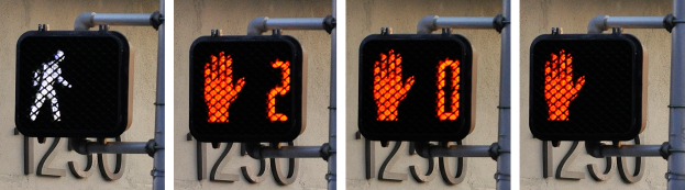 Eine an einem Gebäude angebrachte Ampel, die drei verschiedene Arten von Verkehrssignalen anzeigt: rot, gelb und grün.