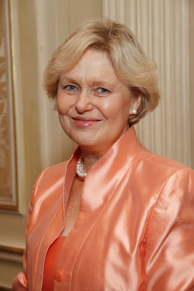 Eine Frau in einem orangen Kleid mit einem Foto Rahmen im Hintergrund.