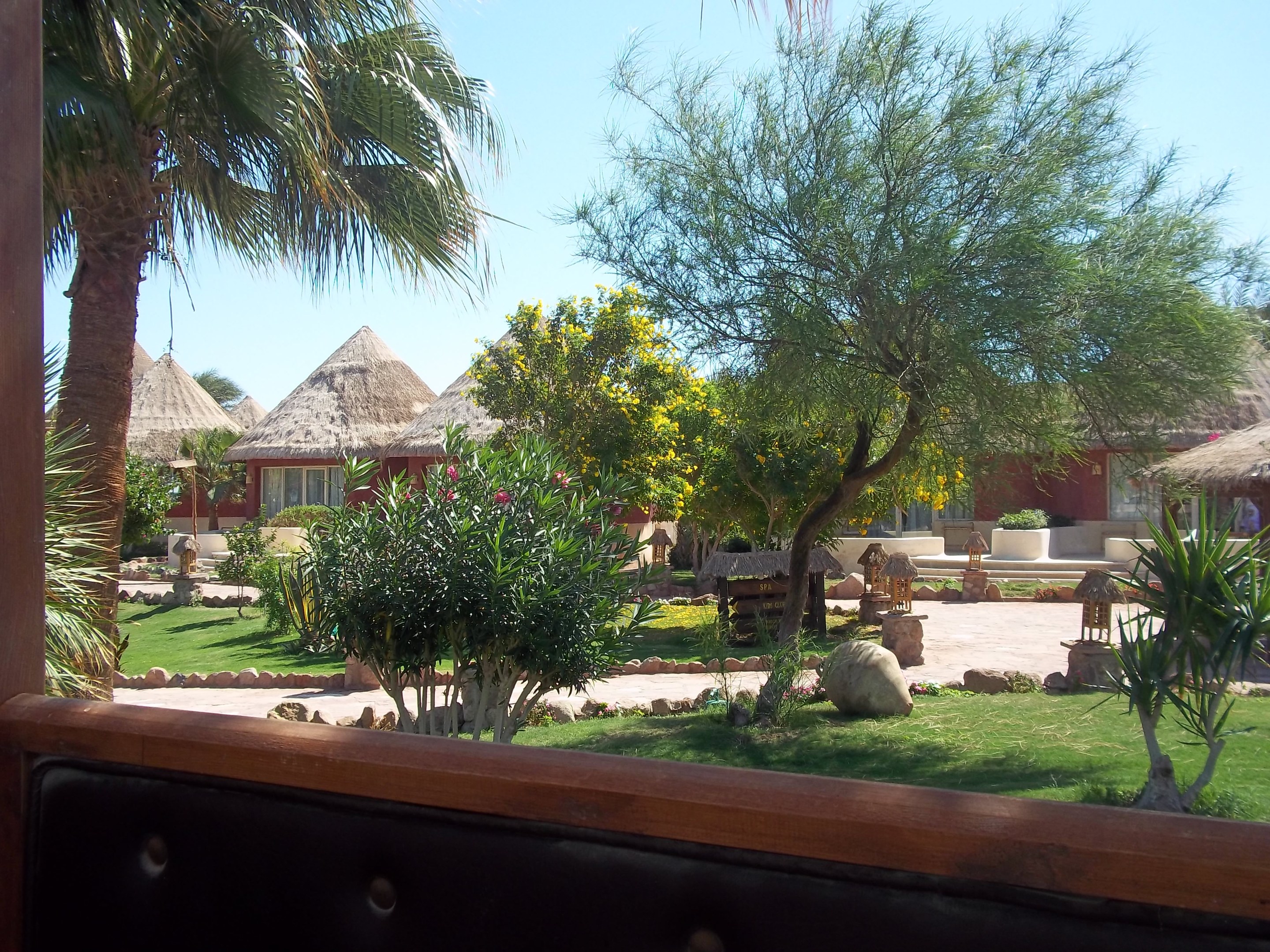 Ein Resort-Blick mit Hütten, Grünpflanzen, Felsen und einer Bank unter einem Himmel-Hintergrund.