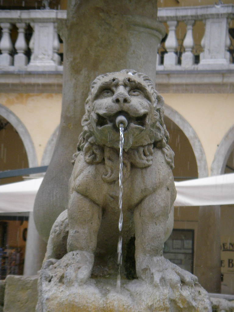 Ein Brunnen mit einem Gebäude im Hintergrund.