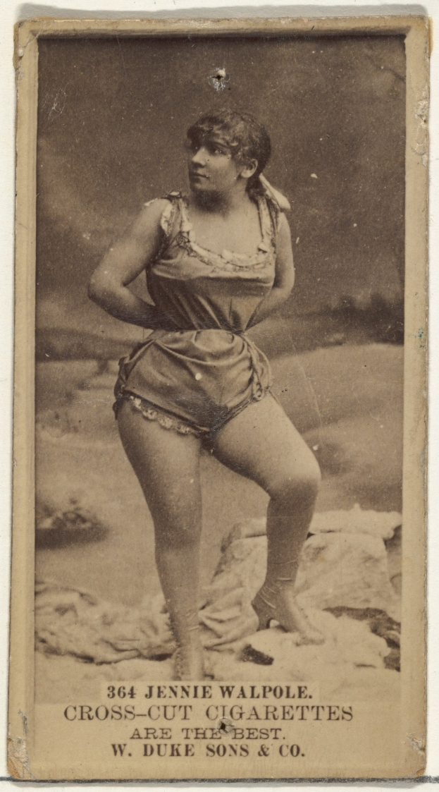Ein altes Foto einer Frau in einem Badeanzug, die selbstbewusst auf einem Strand steht, mit einem Dutt, geschlossenen Augen und einem friedlichen Ausdruck, mit Text unten auf dem Bild.