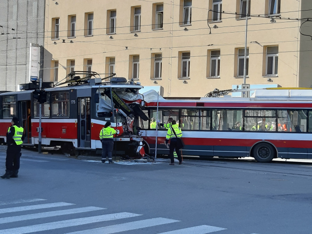 Eine rote und weiße Straßenbahn beteiligt sich an einem Straßenrand-Crash mit einigen Menschen in der Nähe und einem Gebäude im Hintergrund.