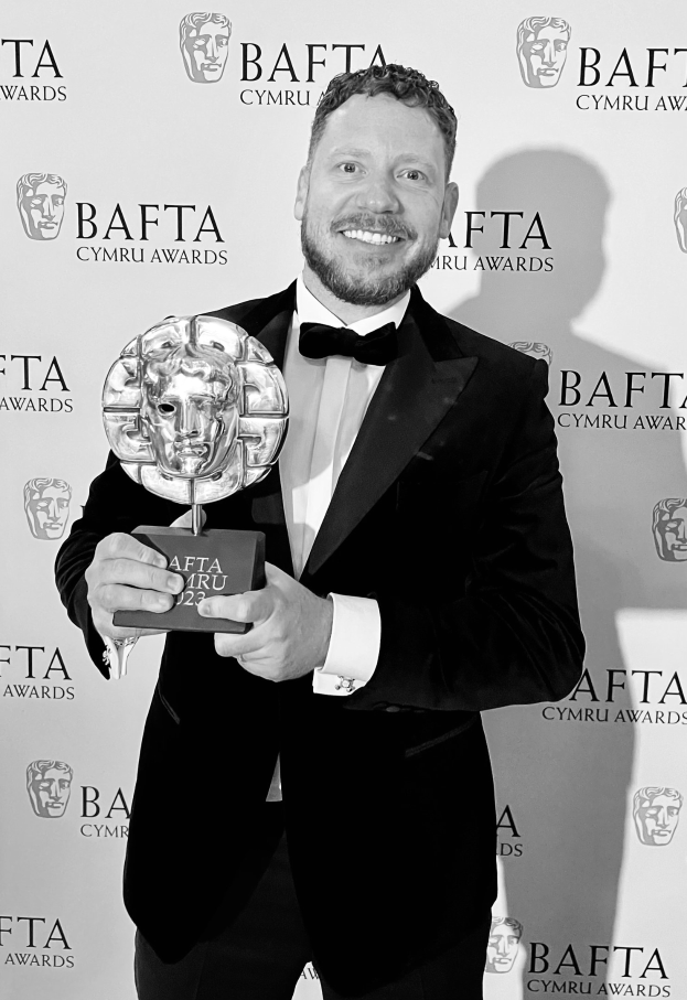 Ein Mann im Smoking hält einen BAFTA-Award und lächelt, vor einem Hintergrund mit der Aufschrift "BAFTA Awards 2018."