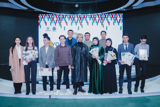 Gruppe von Menschen auf einer Bühne mit Blumensträußen und Urkunden, im Hintergrund ein 'Youth Solar Awards 2019'-Plakat.