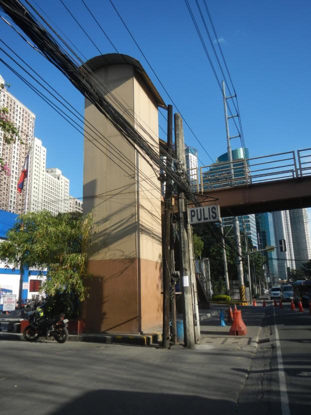 Stadtstraße mit Brücke im Hintergrund, Gebäuden, Bäumen, Polen, Brettern, Verkehrsleitkegeln und Fahrzeugen auf der Straße, mit Stromleitungen entlang der Straße und Himmel oben.