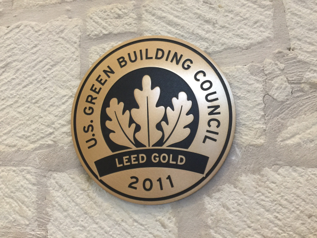 Logo der U.S. Green Building Council an der Außenseite eines Gebäudes, bestehend aus einem grünen Schild mit weißer Umrandung, fetter schwarzer Schrift und einem umgebenden Lorbeerkranz.