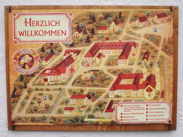 Eine detaillierte Karte von Herzlich Willkommen, Deutschland, die an einer Gebäudewand angebracht ist und Straßen, Gebäude und Sehenswürdigkeiten zeigt, zusammen mit begleitendem Text über die Geschichte, Kultur und Attraktionen der Stadt.