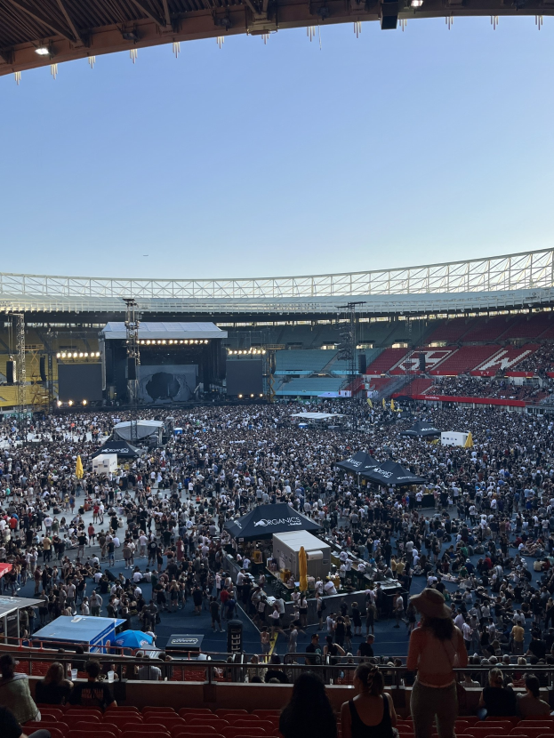 Große Menge sitzend und stehend in einem Stadion mit Zelten, Geländern und Überdachung während eines Events in der O2 Arena in London.